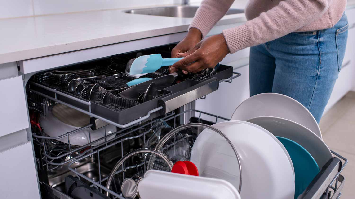 A woman placing utensils in a brand new dishwasher