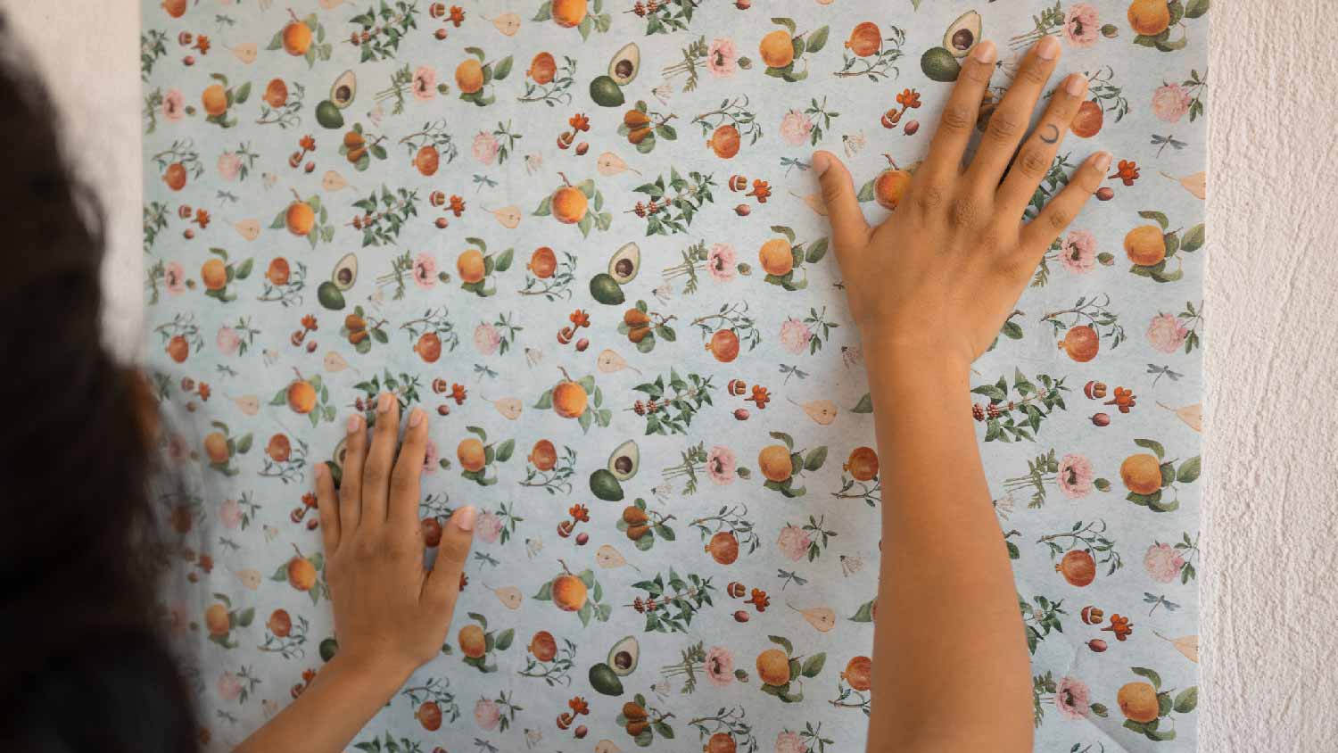 A woman hanging fruit-covered wallpaper