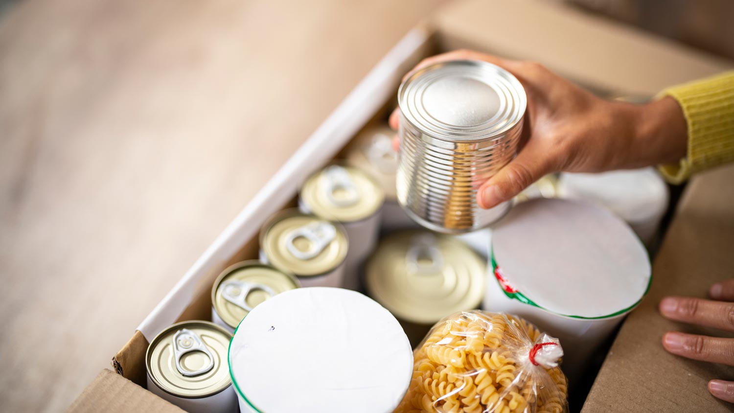 A woman preparing a donation box with canned food
