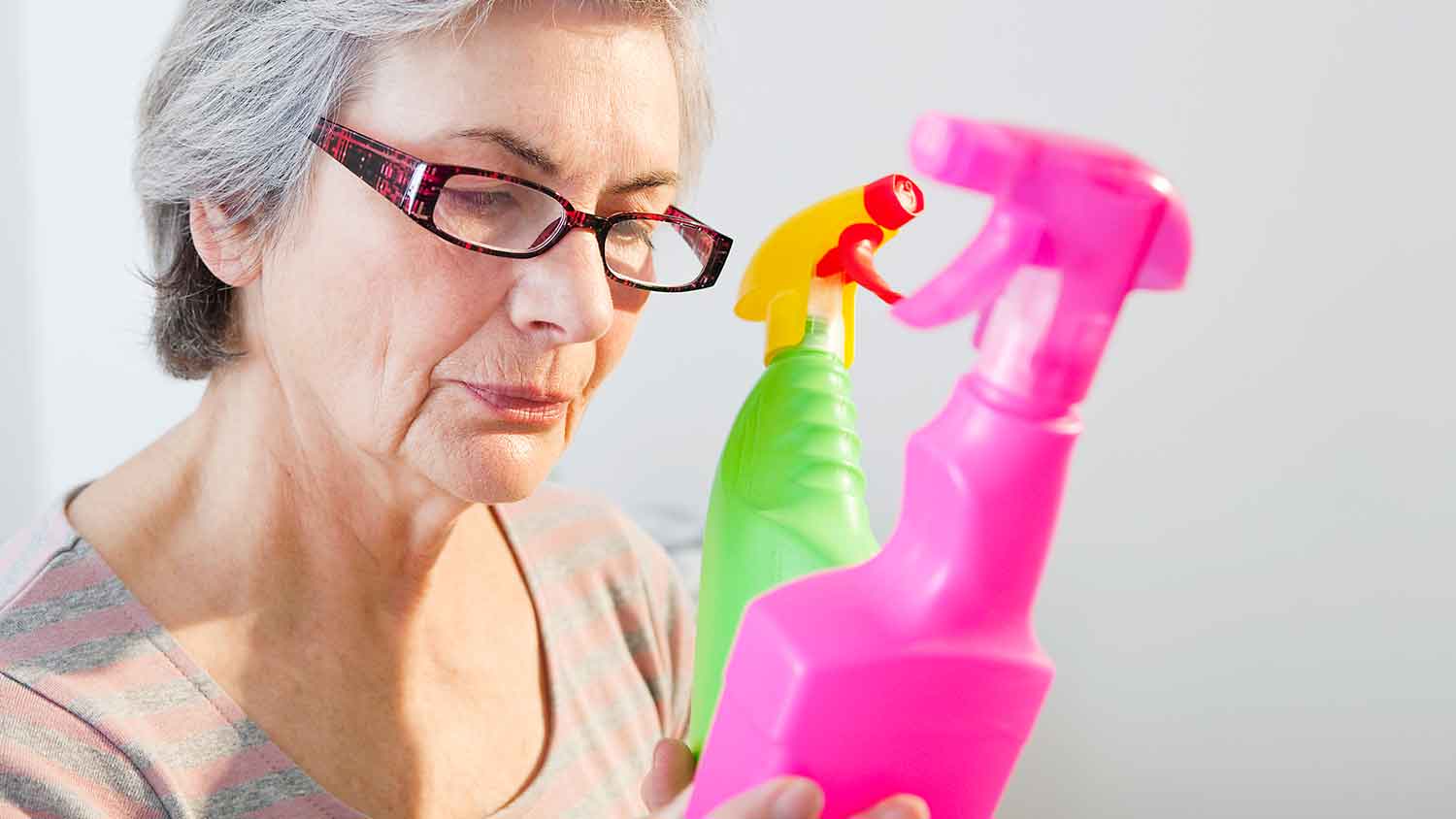 Woman holding cleaning product and reading label