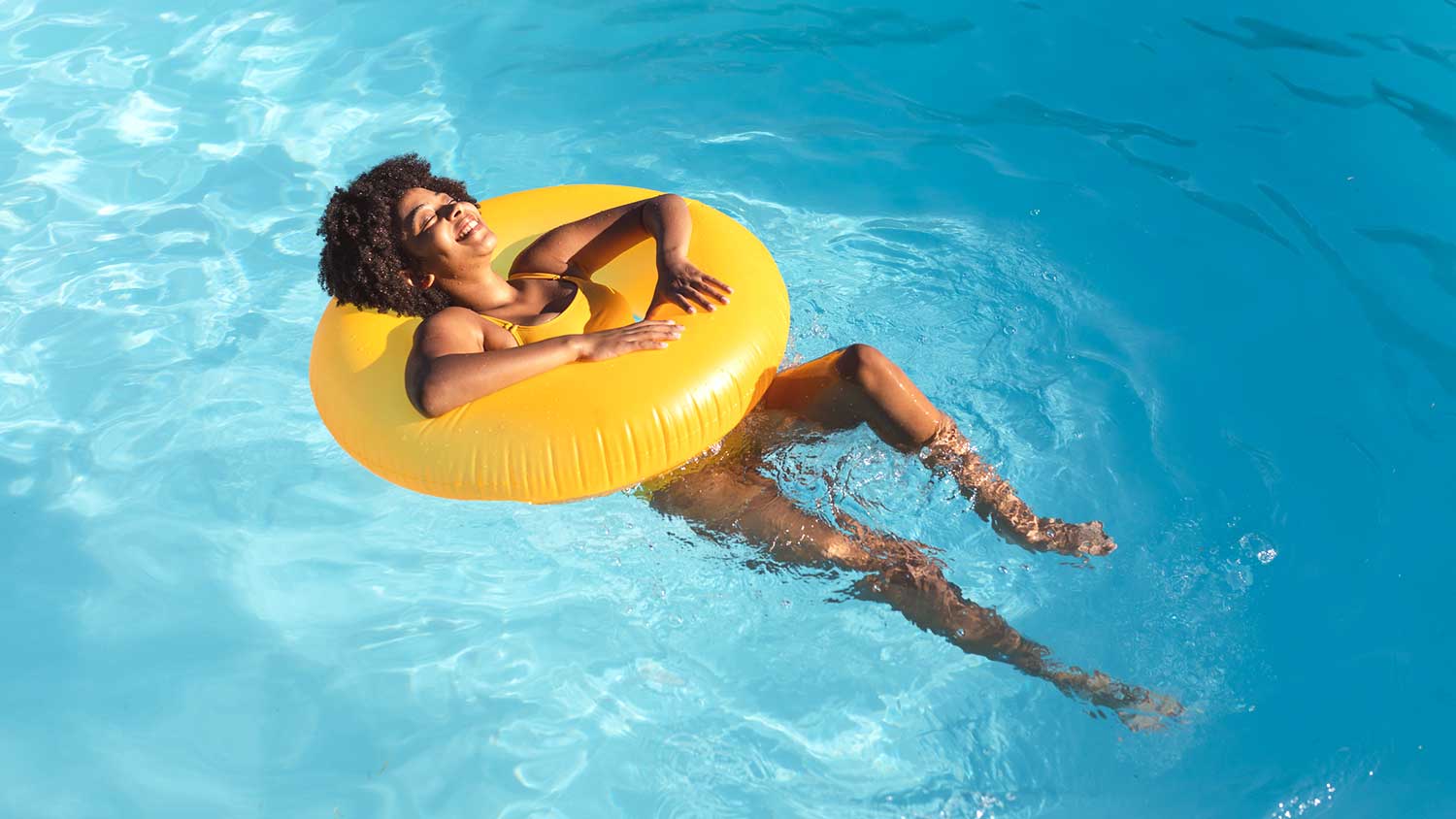 Young woman floating on a pool tube