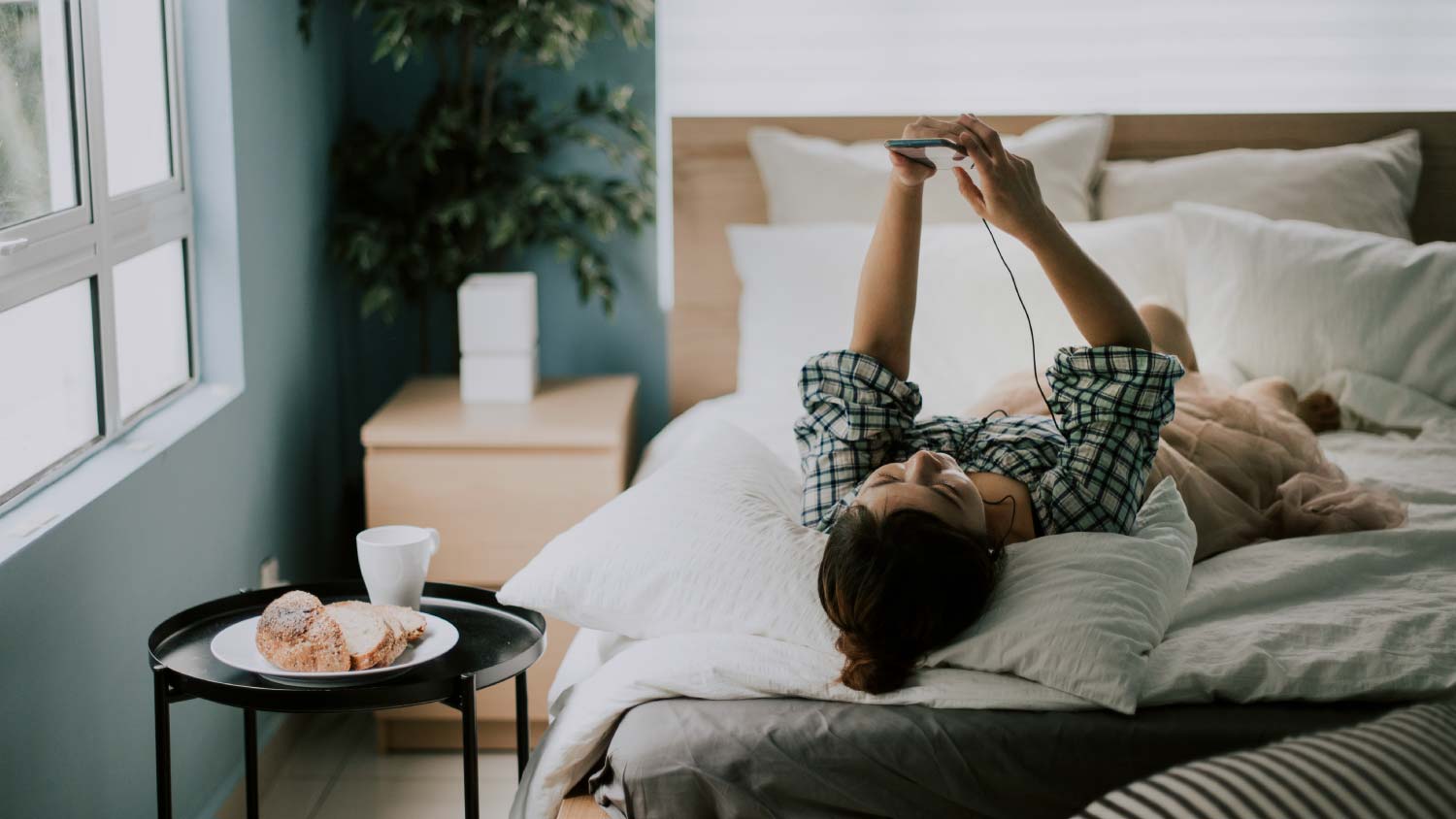 woman lying on bed looking at her phone