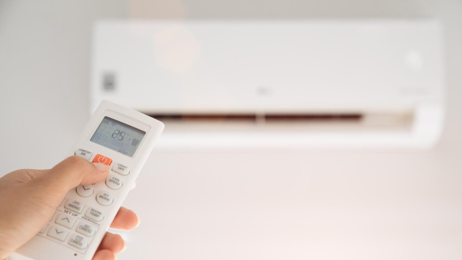 Woman holding remote controller directed on the air conditioner