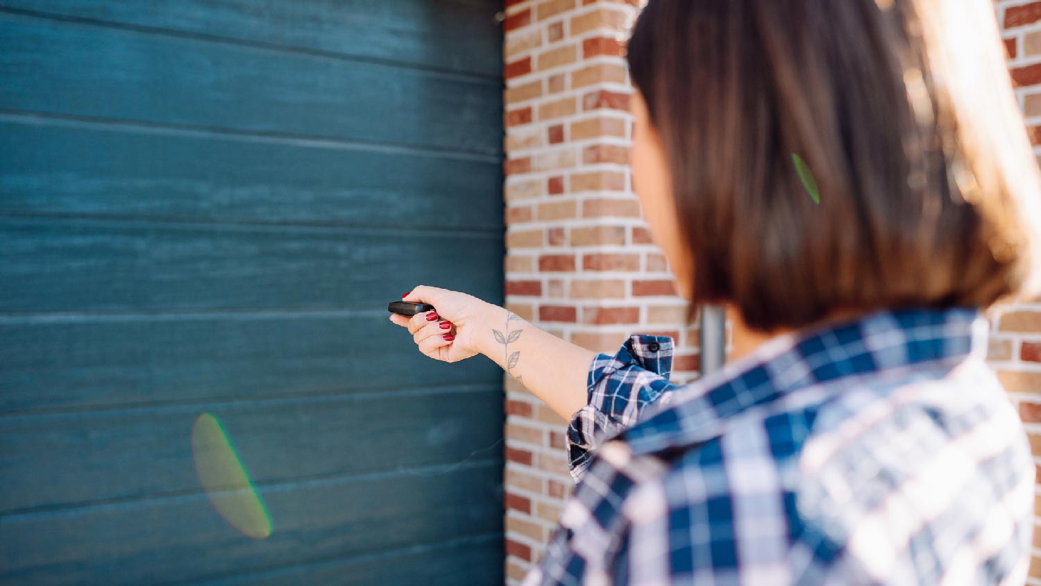 A woman using a remote keypad to open a garage door