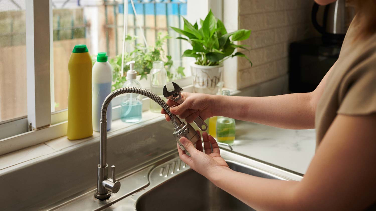 A woman repairing her kitchen faucet