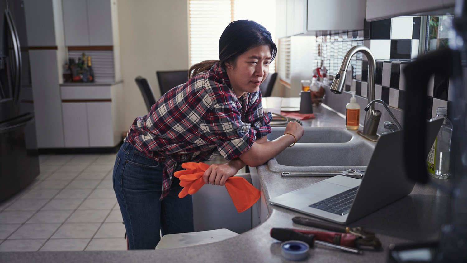 A woman repairing her kitchen faucet