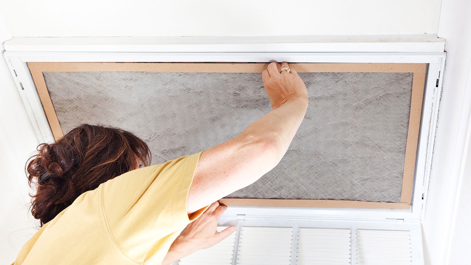 A woman replaces an air conditioner filter