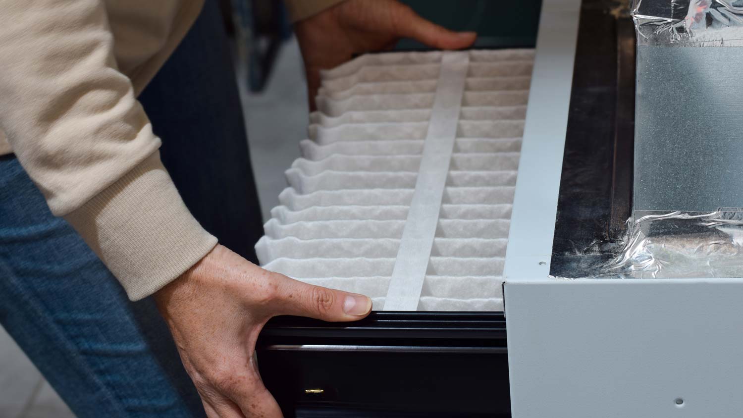 A woman replacing the filter of a furnace