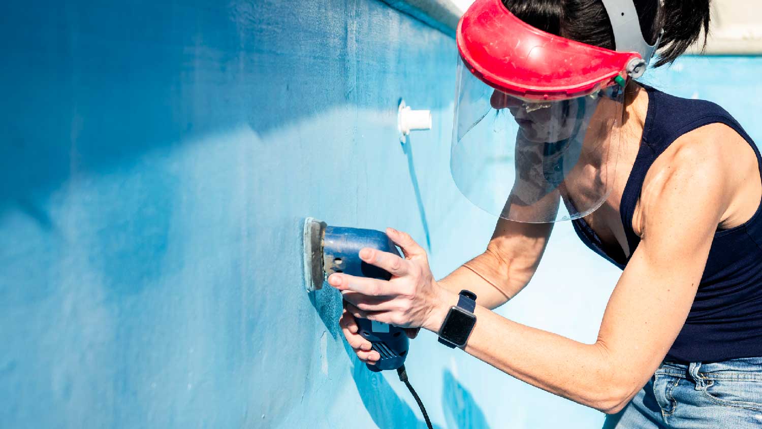 A woman sanding the pool’s walls