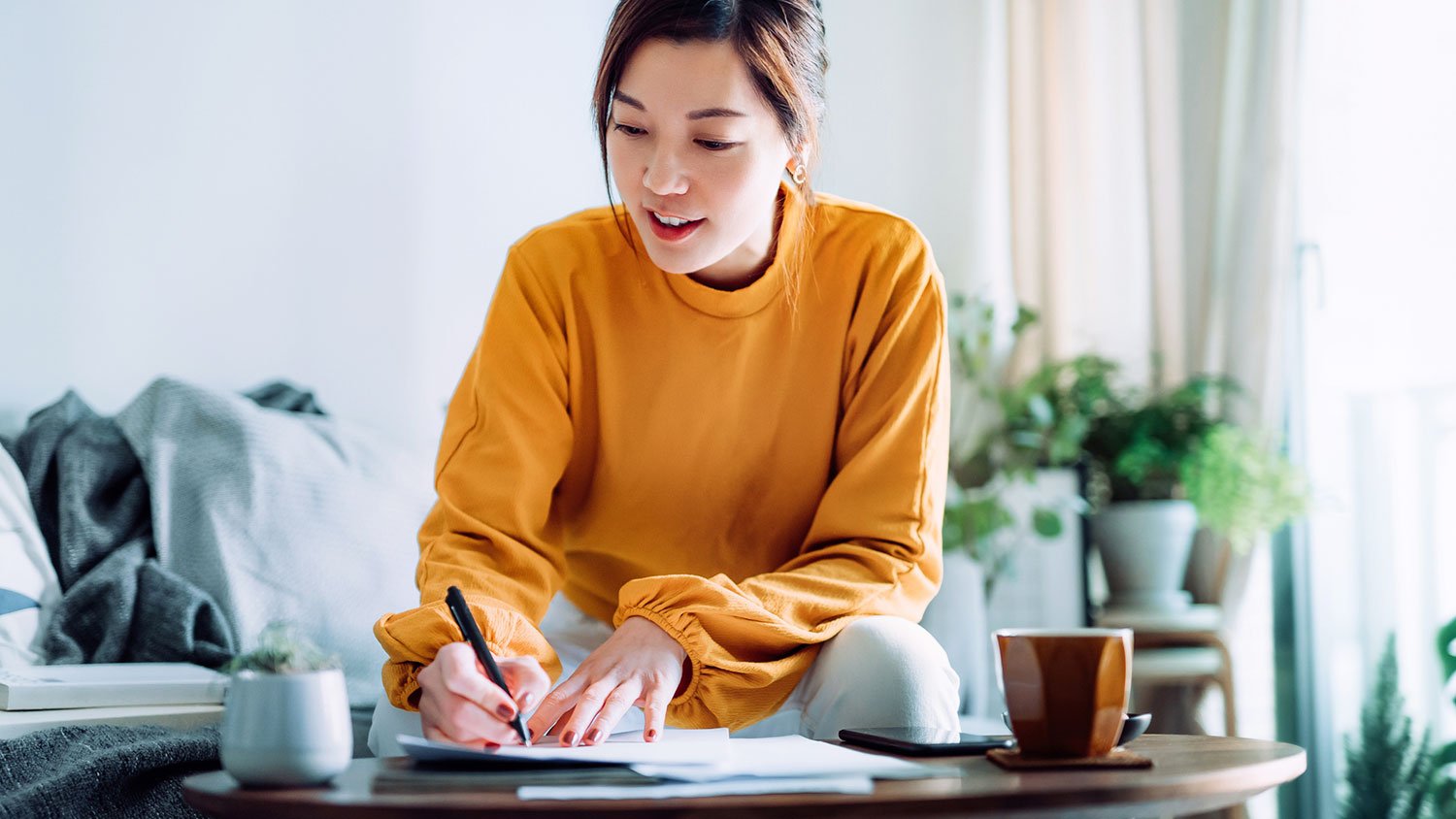 Woman in her living room is signing paperwork