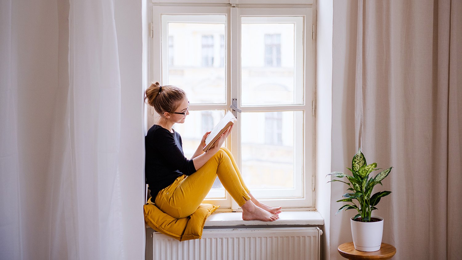 woman reading a book by the window 