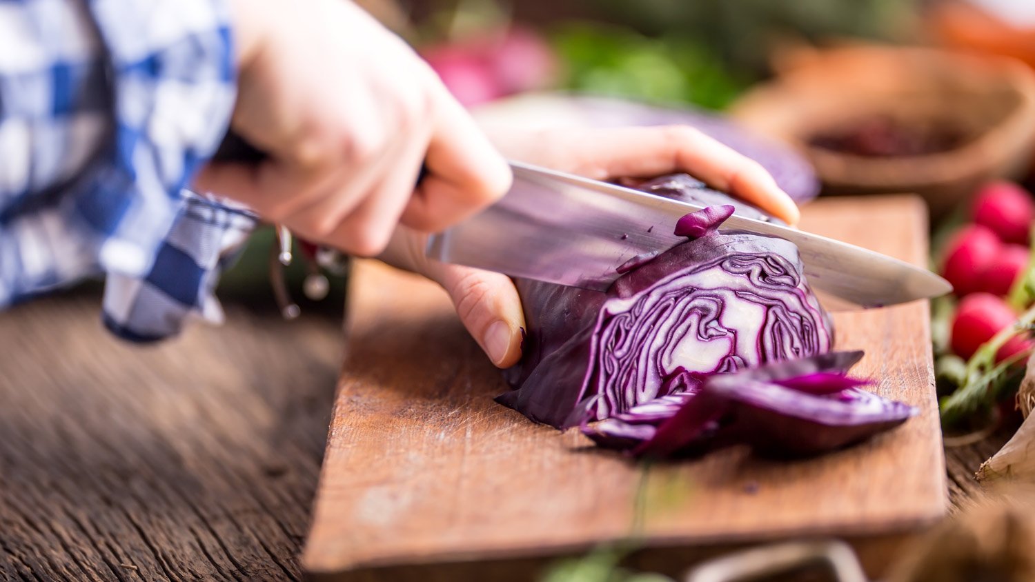 A woman’s hands slicing cabbage with knife