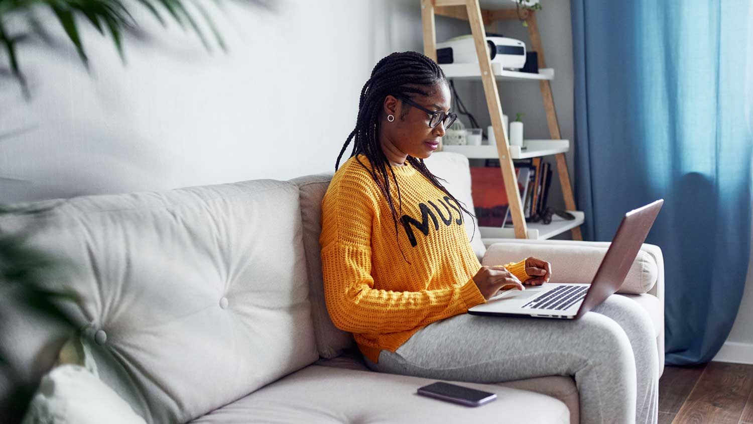 A woman sitting on a sofa working on her laptop