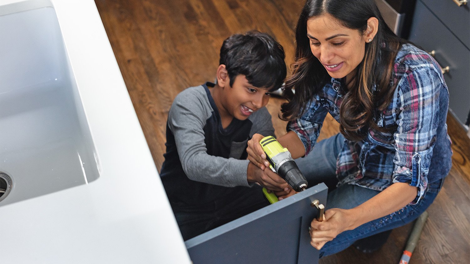 woman and son installing cabinet hardware