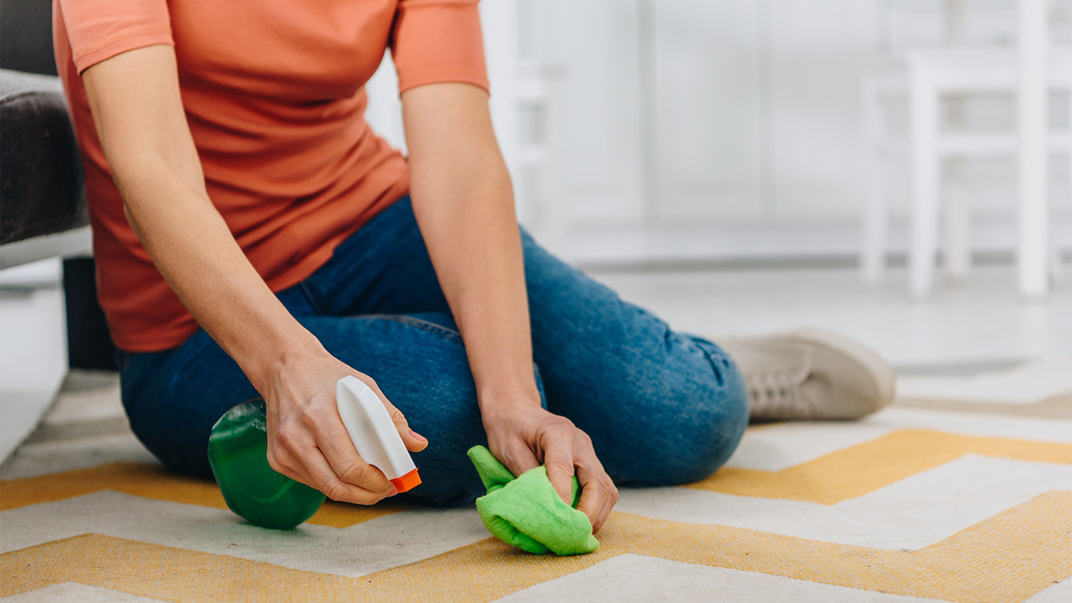 woman spraying cleaning solution on carpet  