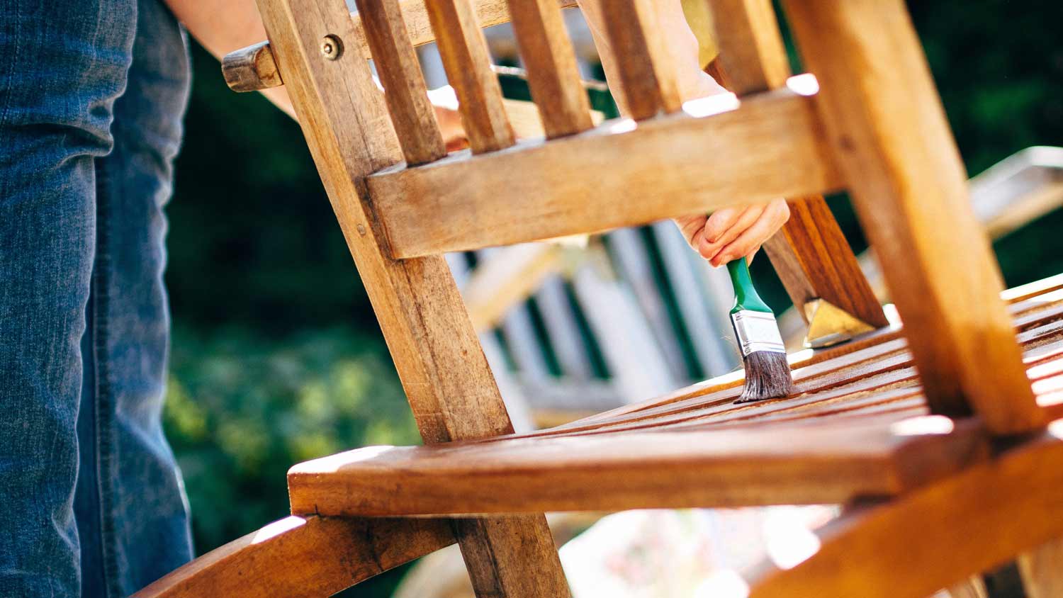 woman staining wood garden chair