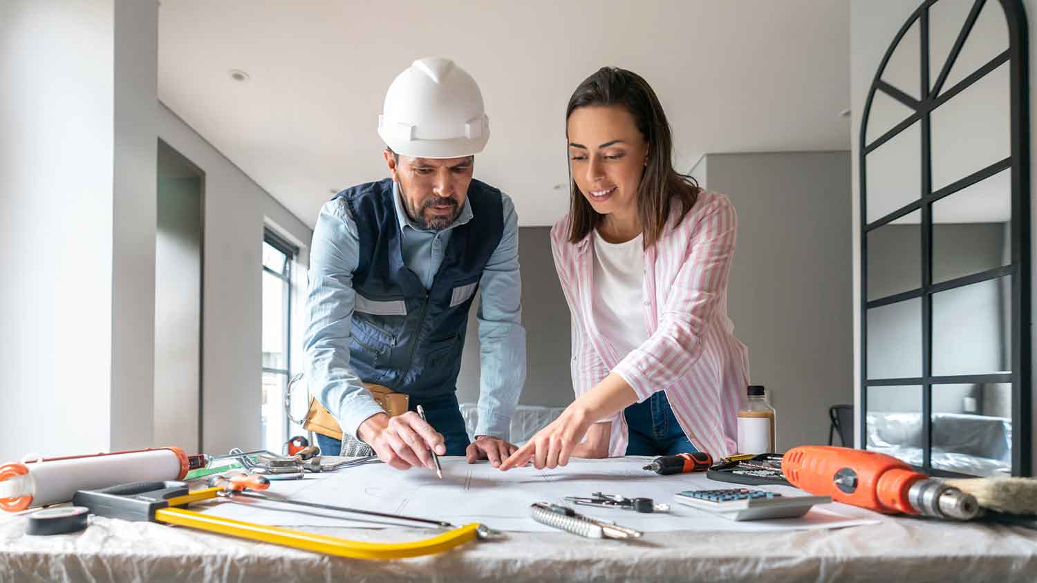 Woman and concrete contractor reviewing blueprints