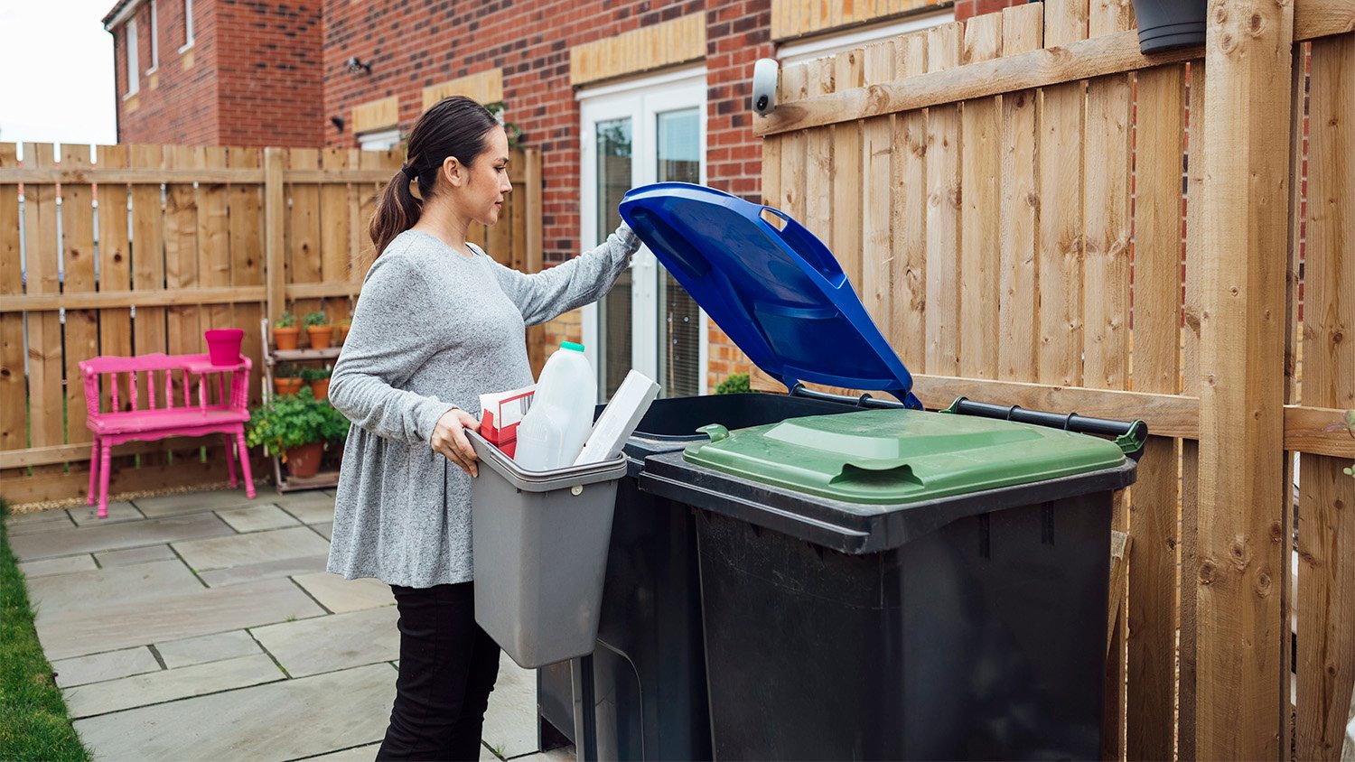 woman throwing away trash in yard.