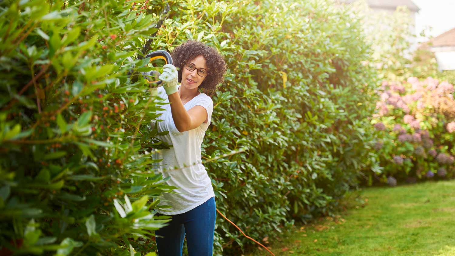 A woman trimming bushes in her garden
