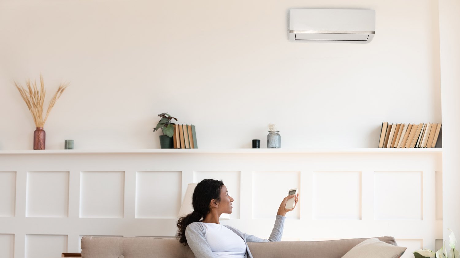 A woman sitting on sofa turning on the AC