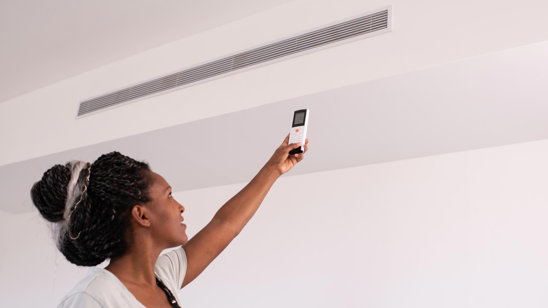 A woman turning on the air conditioner