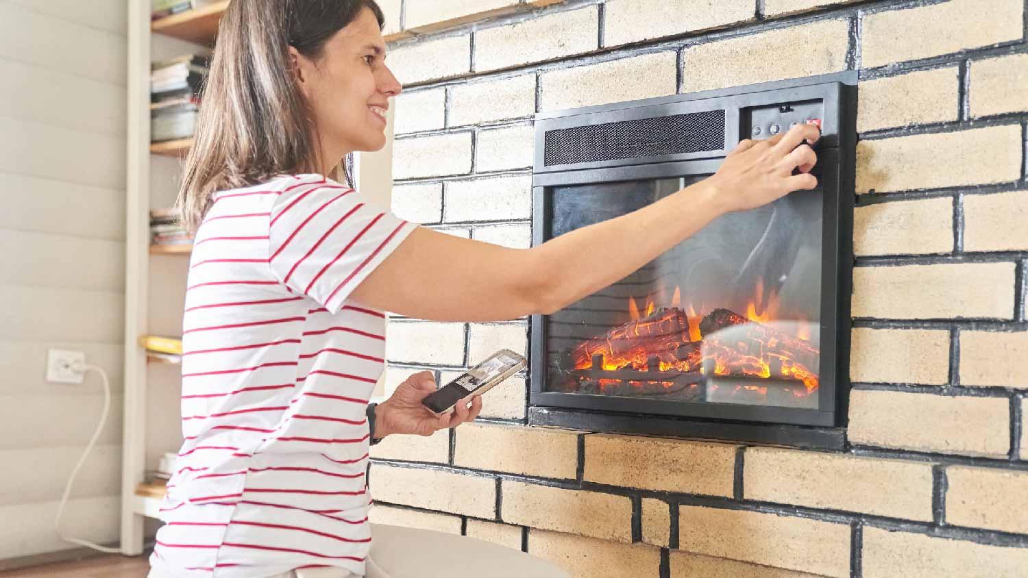 A woman turning on an electric fireplace