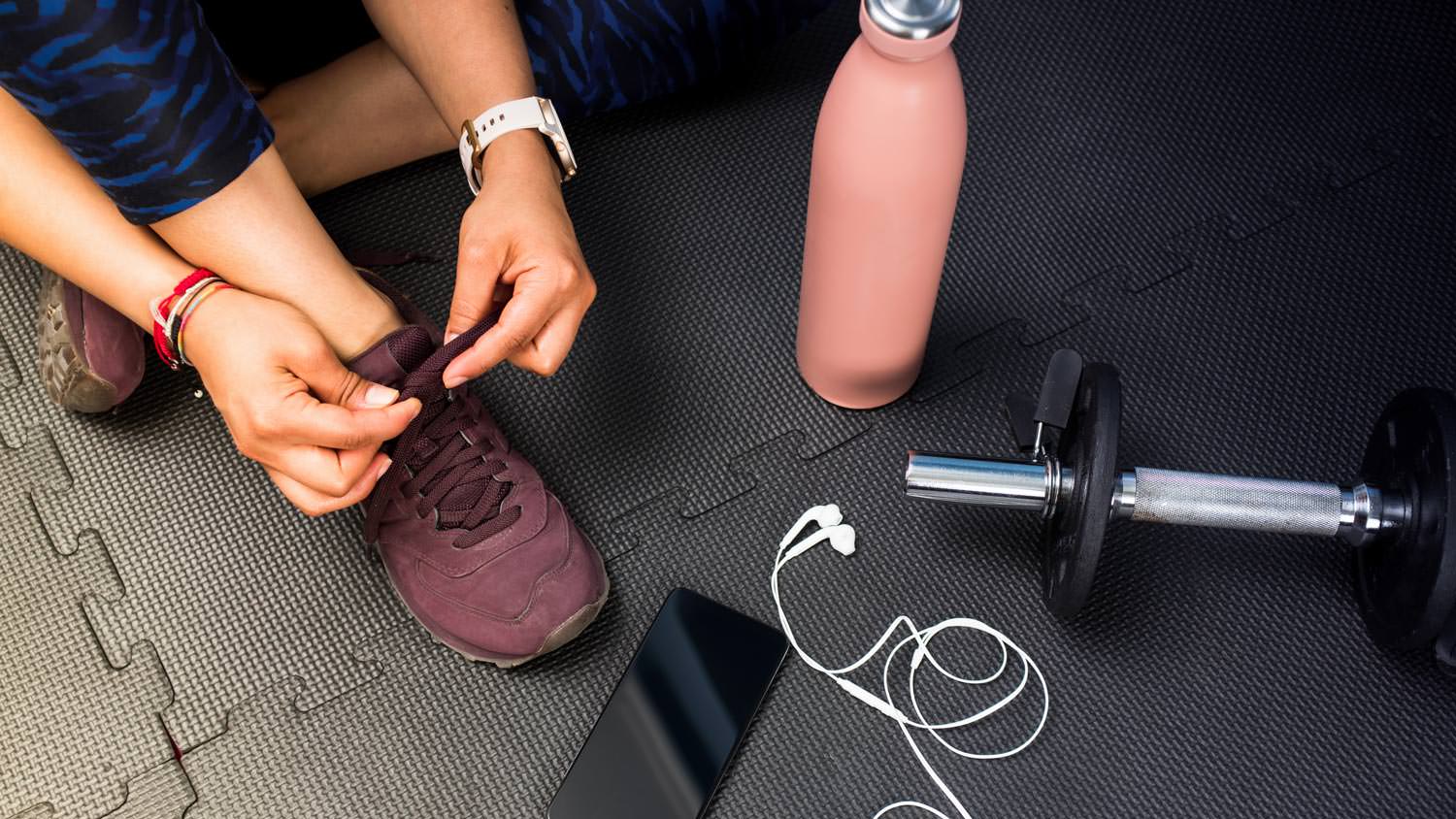 Close-up of a woman tying her shoes on a rubber floor
