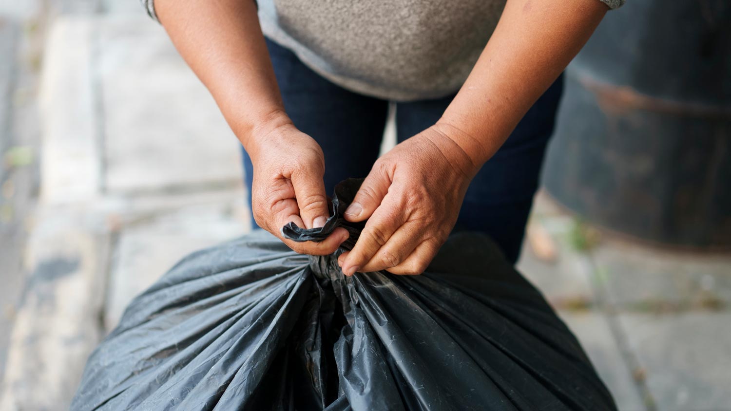 A woman tying a trash bag