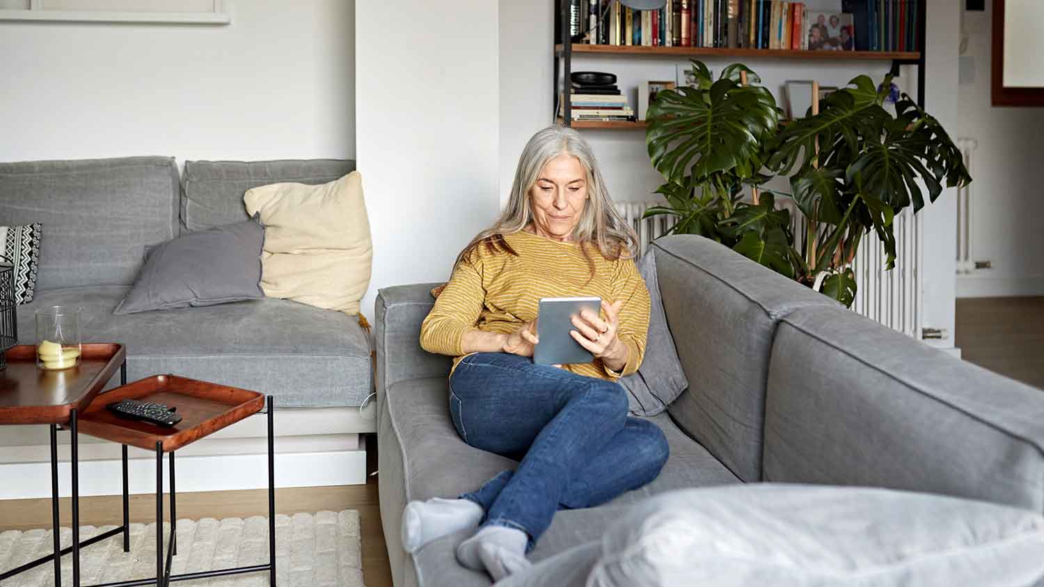 Woman sitting on the couch reading on a tablet