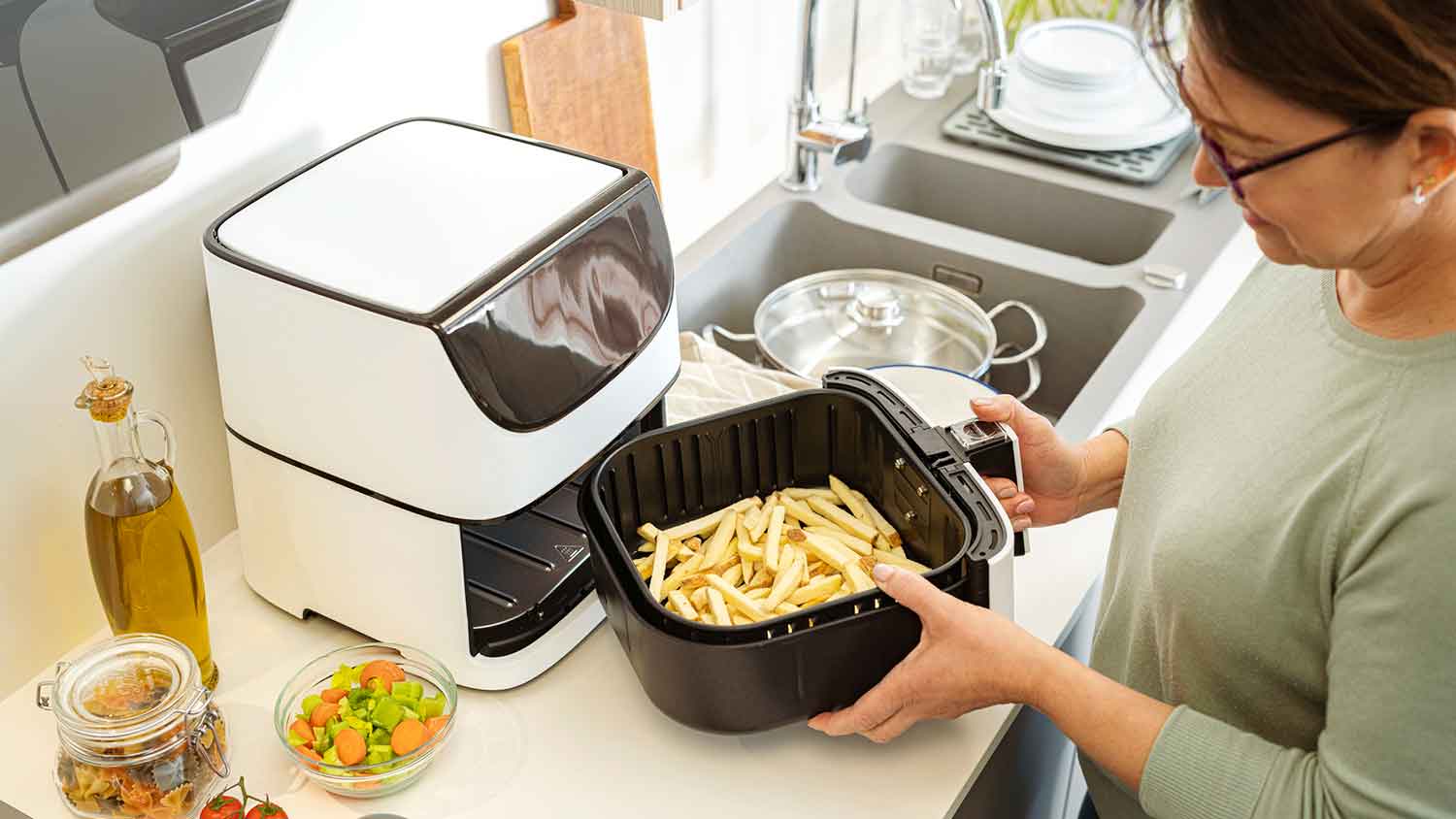 Woman cooking French fries in an air fryer