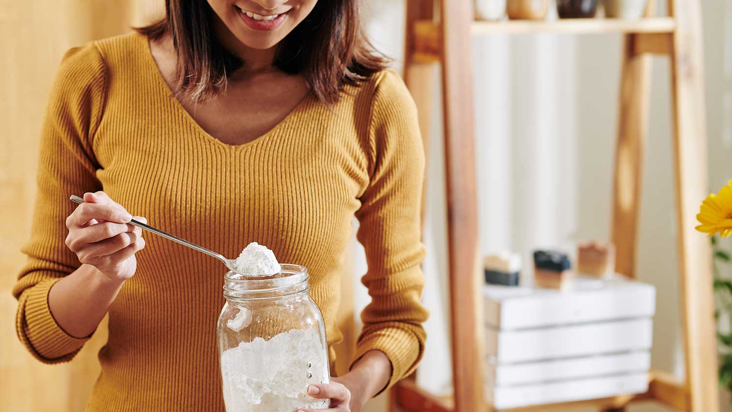 Woman holding a spoon and a jar with baking soda