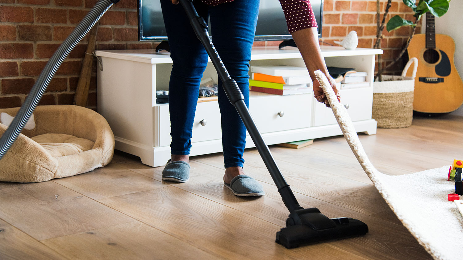 woman vacuuming under a rug in her living room