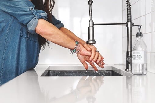  Woman washes hands in kitchen sink