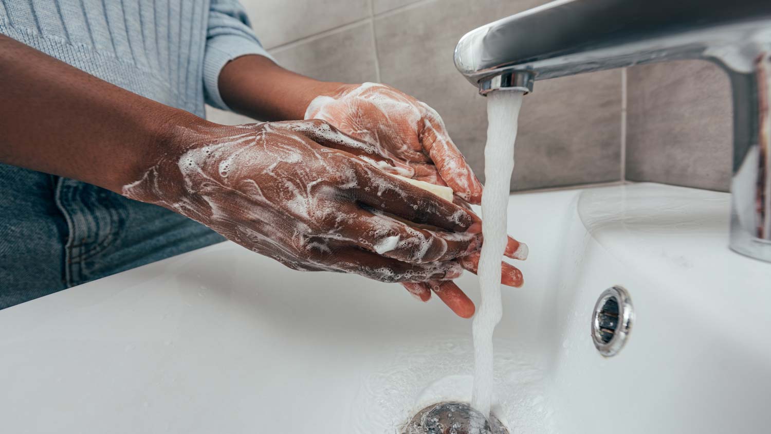 A woman washing her hands in a bathroom sink