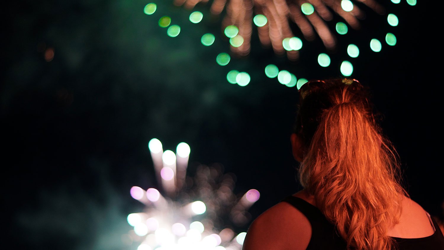 Closeup of a woman watching fireworks against the dark sky