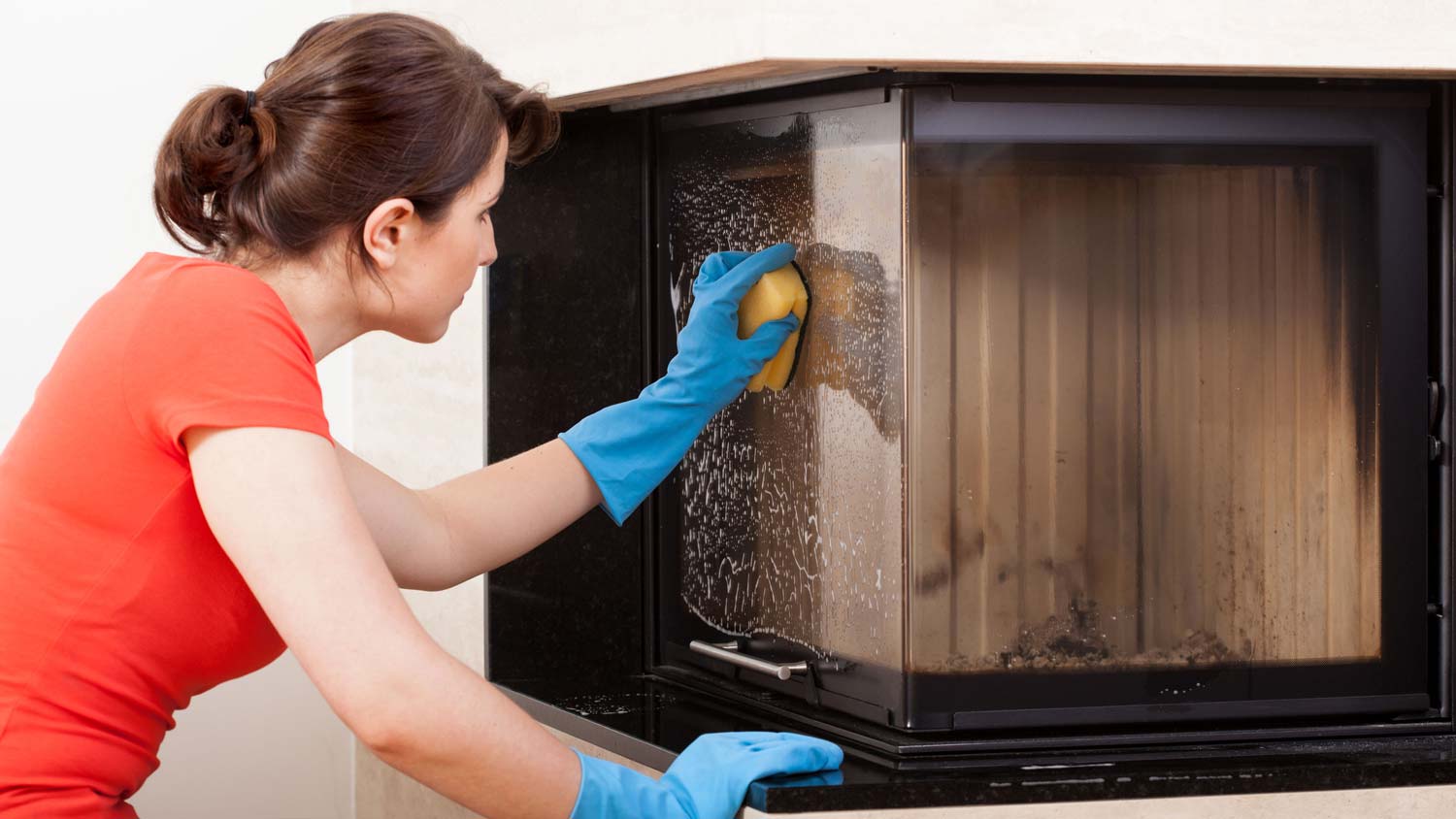 A woman wiping the exterior of a fireplace