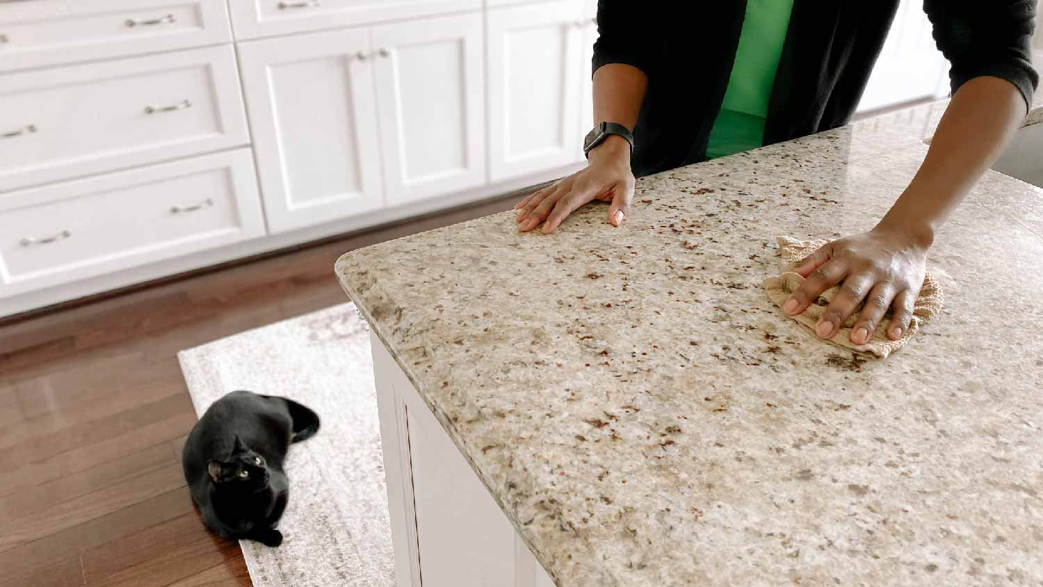 A woman wiping a granite countertop