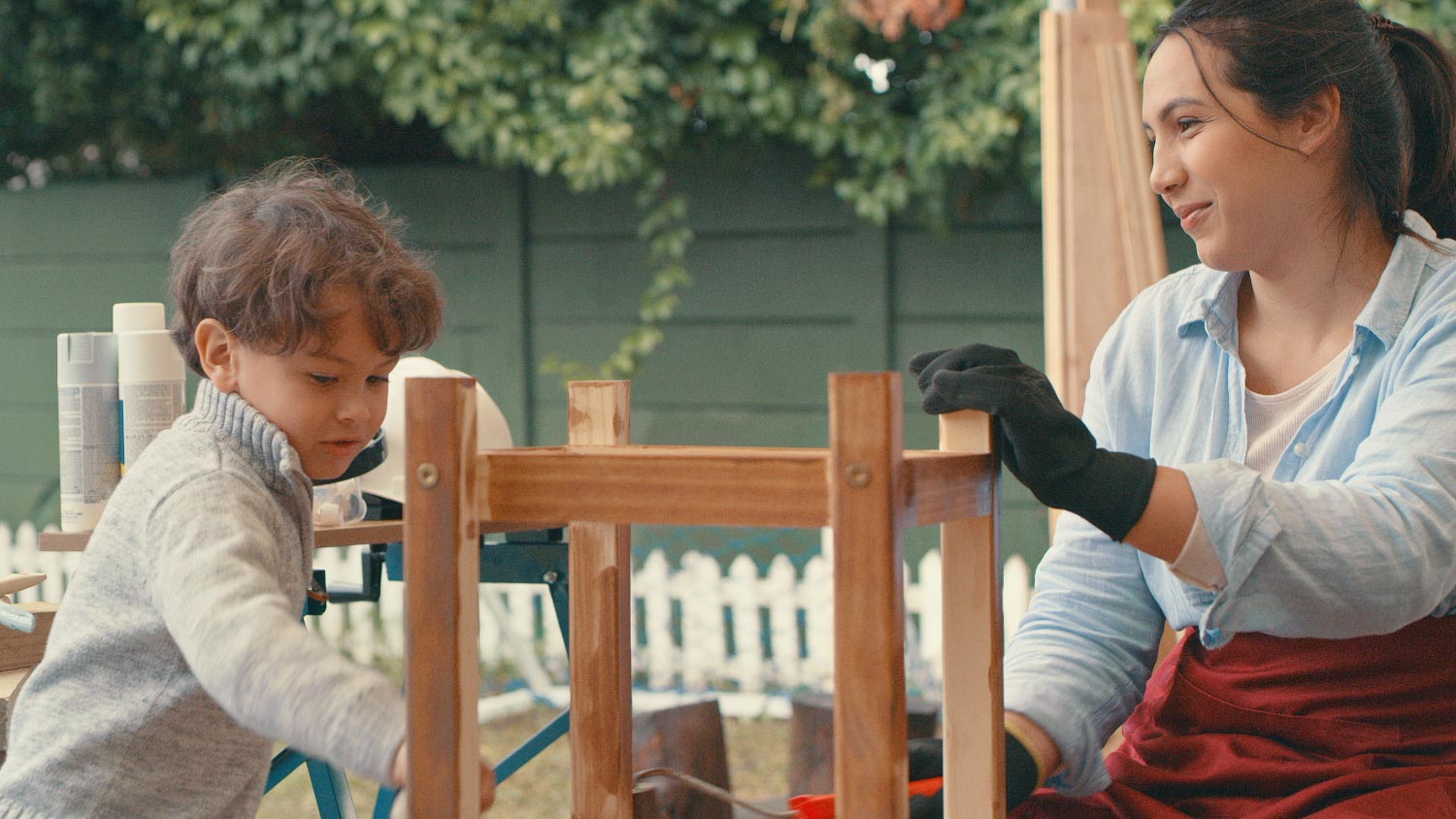 A woman working on a wooden project with her son