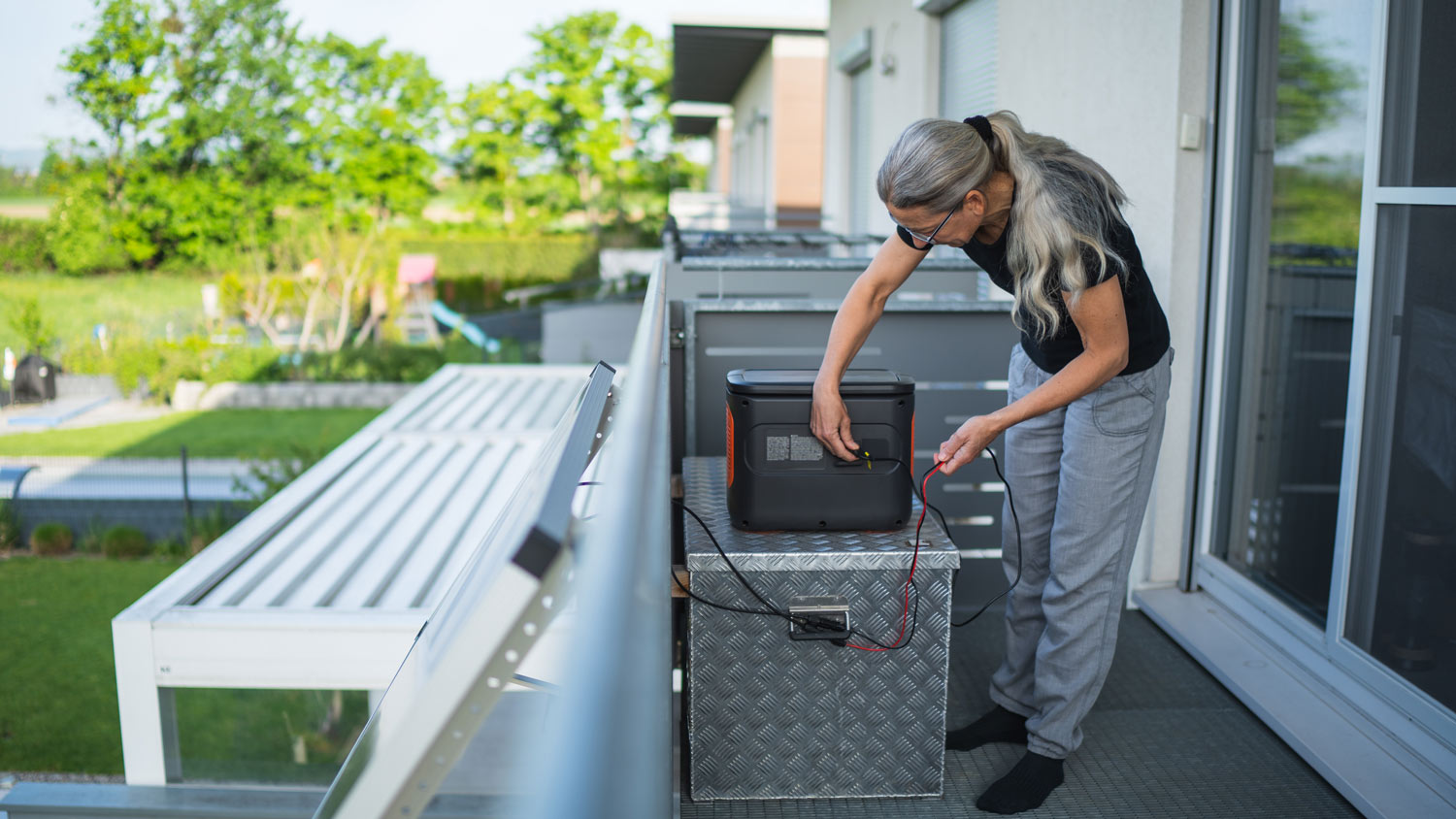 Woman plugging in cable from solar panel in rechargeable portable power station