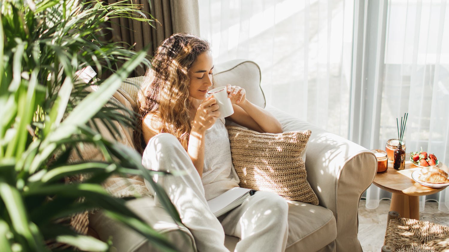 Woman at home reading book and drinking coffee