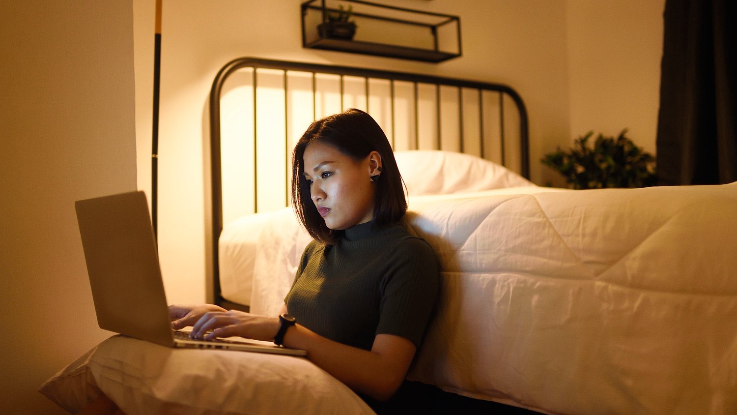 Woman working on laptop in bedroom