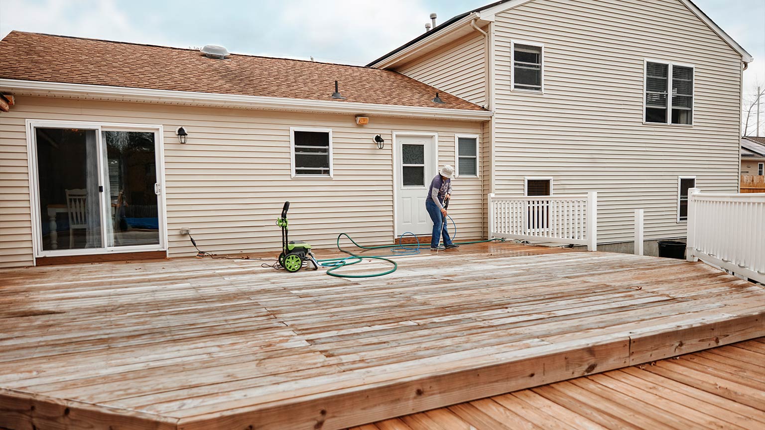 Woman Cleaning Wooden Terrace With A High Water Pressure Cleaner