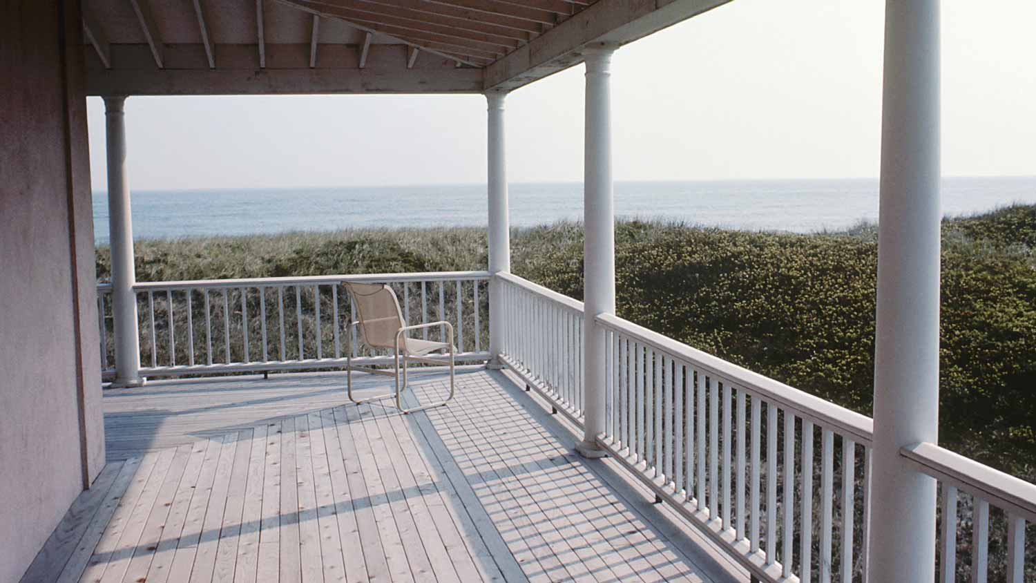 : A wooden deck wrapping around a house overlooking the sea