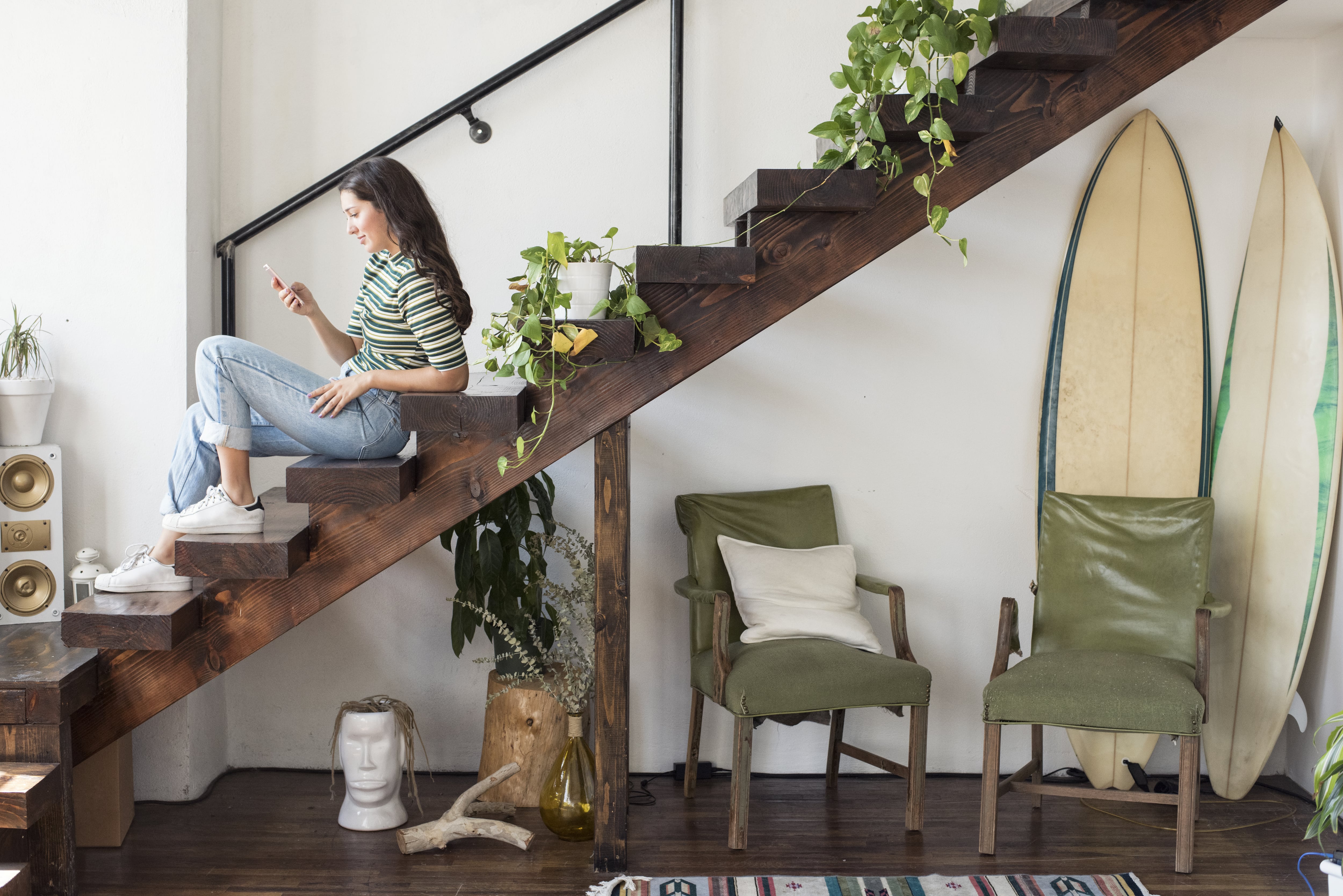 Woman sitting on floating staircase with potted plants on the steps