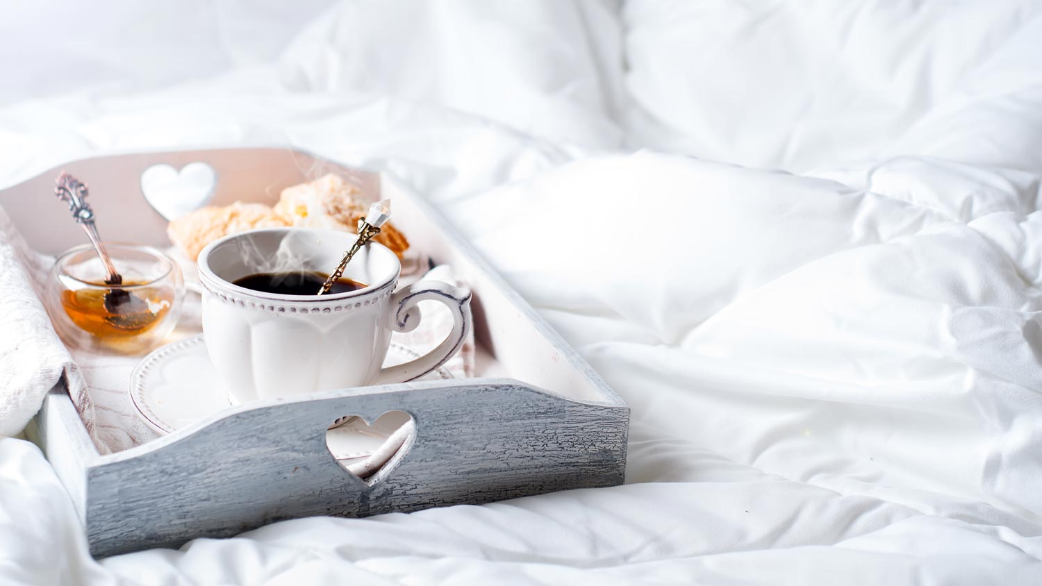 A wooden tray with light breakfast on bed