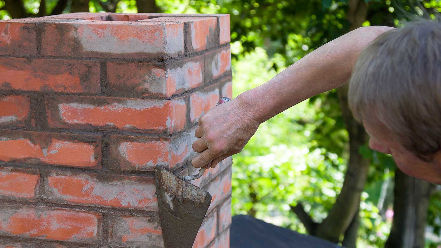 Worker building a red brick chimney