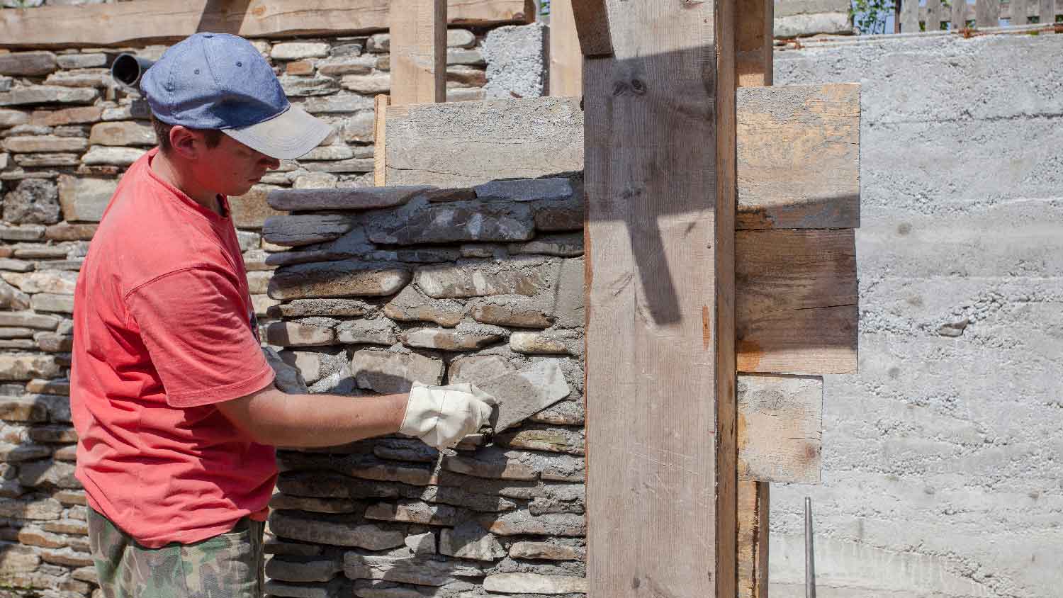 A worker building a stone house