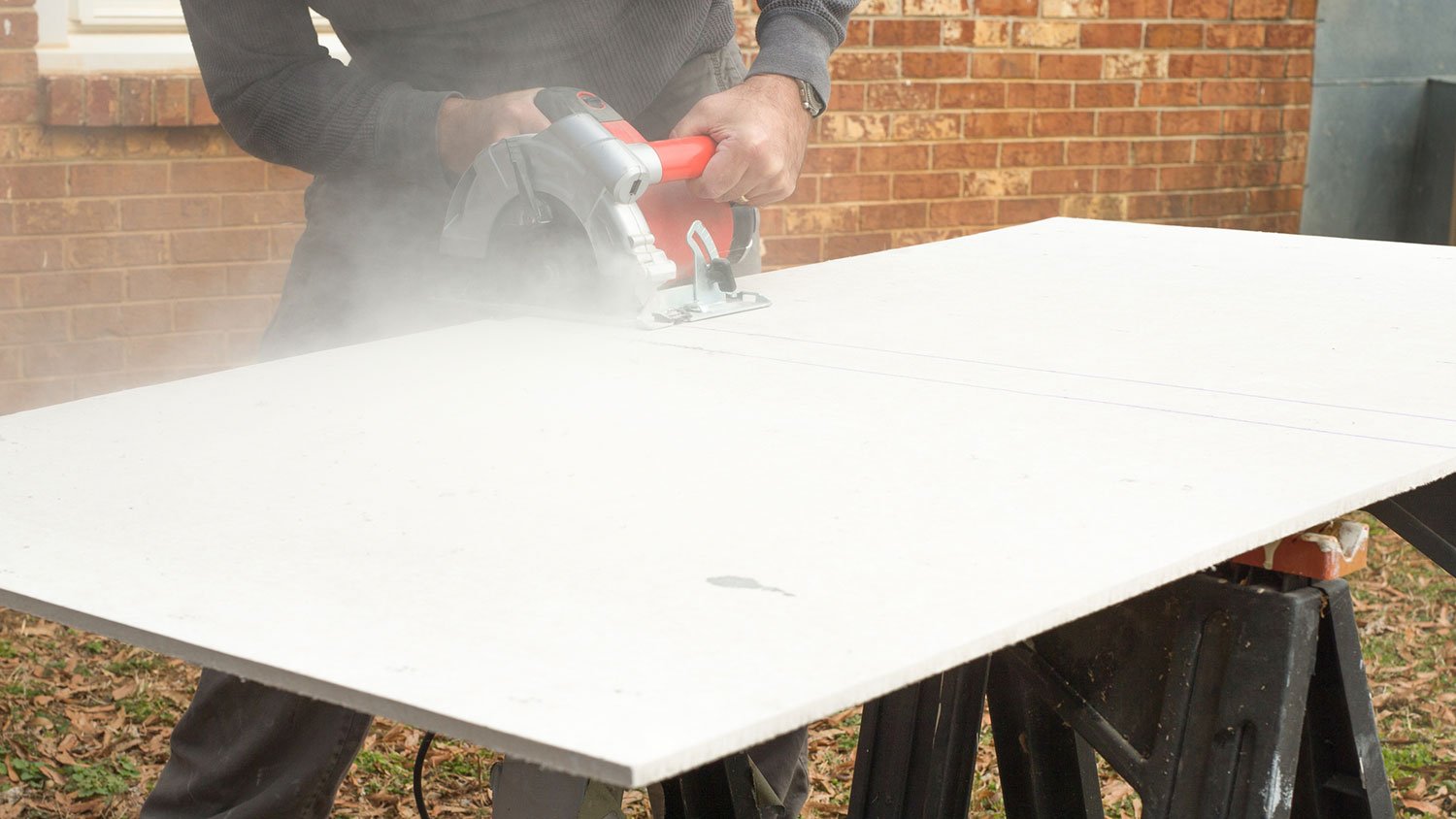 Worker using circular saw to cut a cement board 