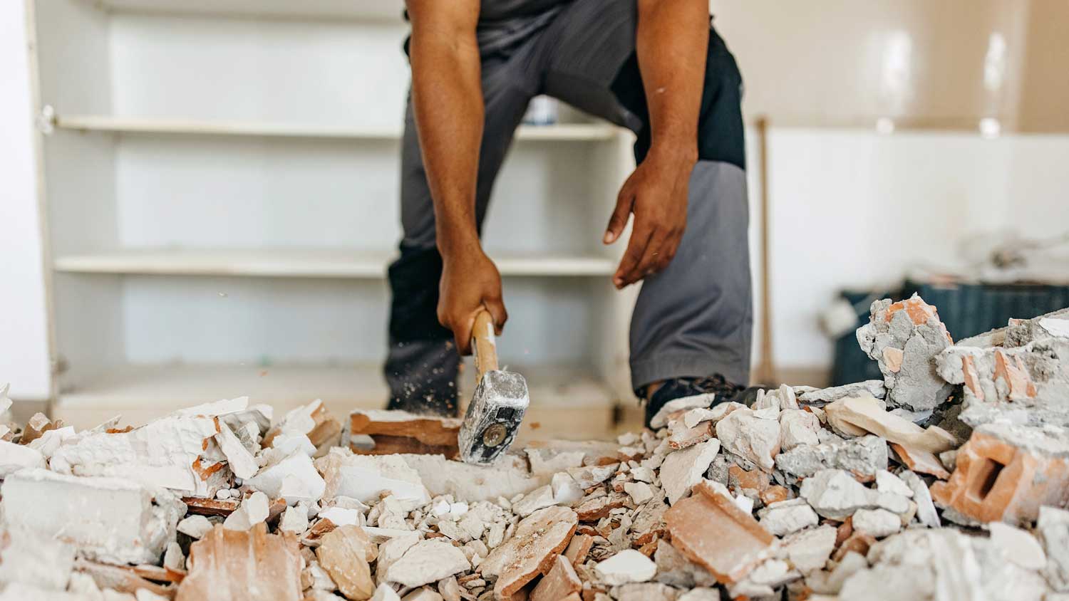 A worker demolishing a wall