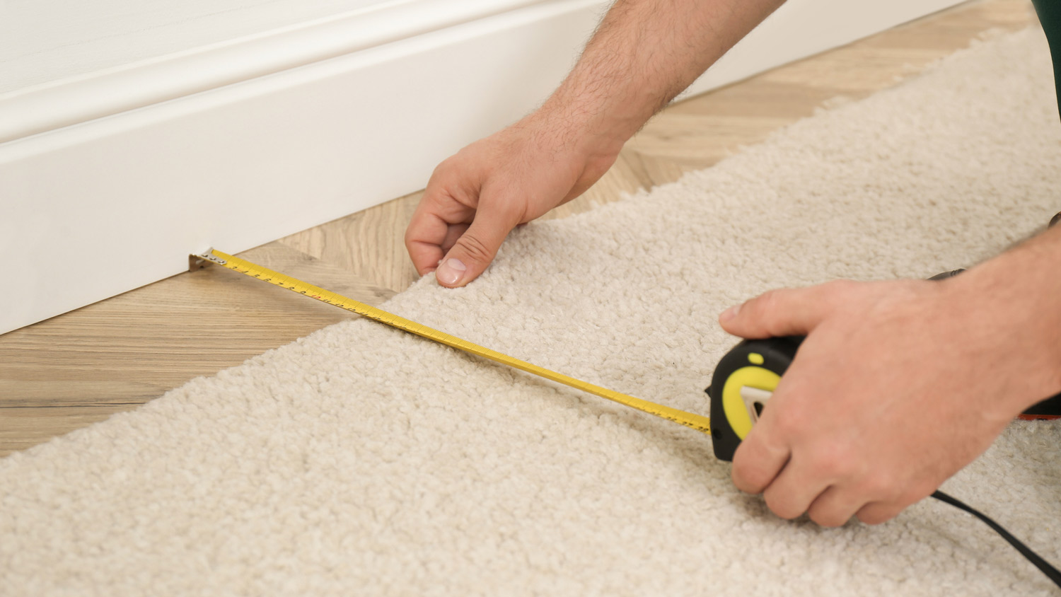 Close-up of a worker measuring while installing new carpet